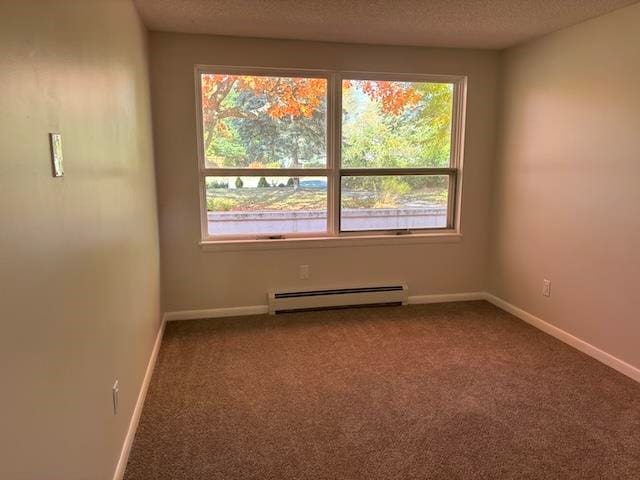 empty room featuring plenty of natural light, carpet, a baseboard radiator, and a textured ceiling