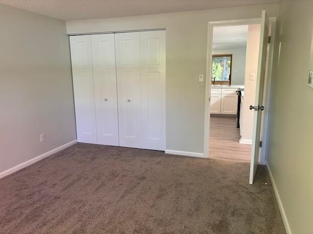 unfurnished bedroom featuring a closet and dark carpet