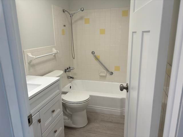 full bathroom with toilet, hardwood / wood-style flooring, vanity, tile walls, and tiled shower / bath