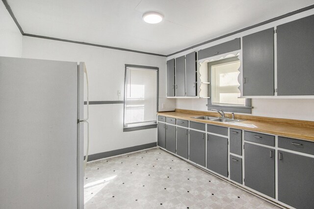 311 Bessie St, Kalamazoo, MI 49007 - kitchen featuring freestanding refrigerator, a sink, gray cabinets, light floors, and baseboards
