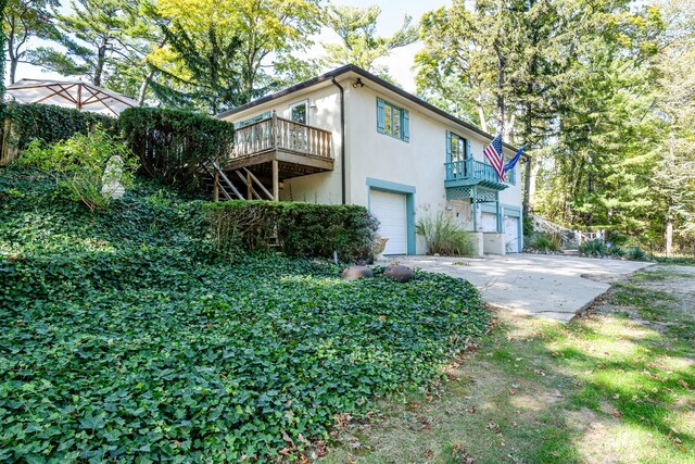 5876 Dunham Ln, Stevensville, MI 49127 - view of property exterior with a garage, stucco siding, concrete driveway, and a wooden deck