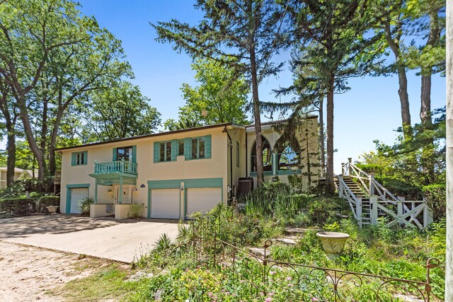 5876 Dunham Ln, Stevensville, MI 49127 - view of front of house featuring stucco siding, a garage, dirt driveway, stairway, and a balcony