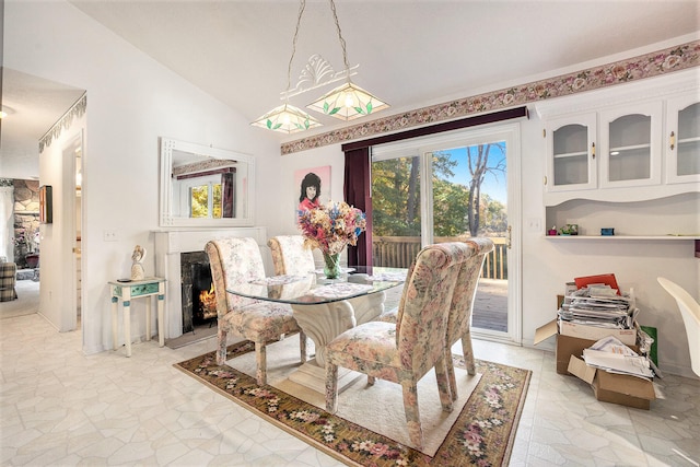 dining space featuring a high end fireplace and vaulted ceiling