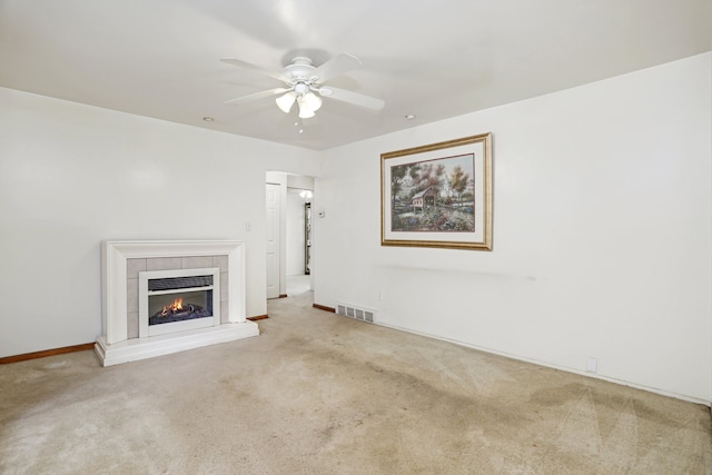 unfurnished living room with ceiling fan, a fireplace, and carpet