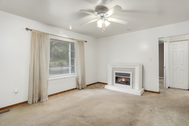 unfurnished living room with light carpet, a tile fireplace, and ceiling fan