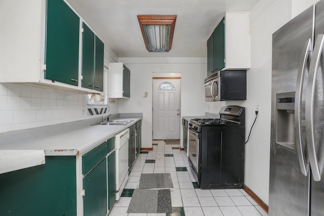 kitchen with appliances with stainless steel finishes, tasteful backsplash, sink, light tile patterned floors, and green cabinets