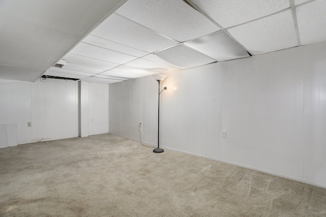 basement featuring a paneled ceiling and light colored carpet