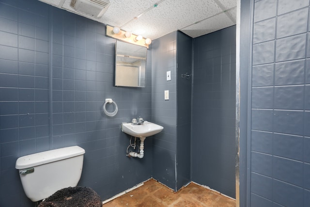 bathroom featuring sink, toilet, and tile walls