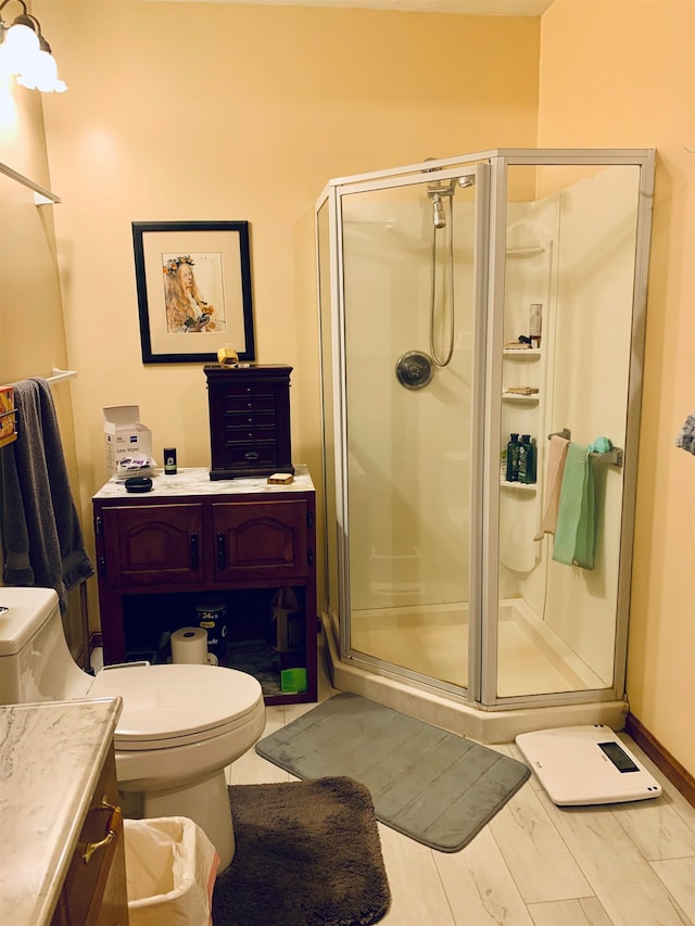 bathroom featuring toilet, vanity, a shower with shower door, and hardwood / wood-style flooring