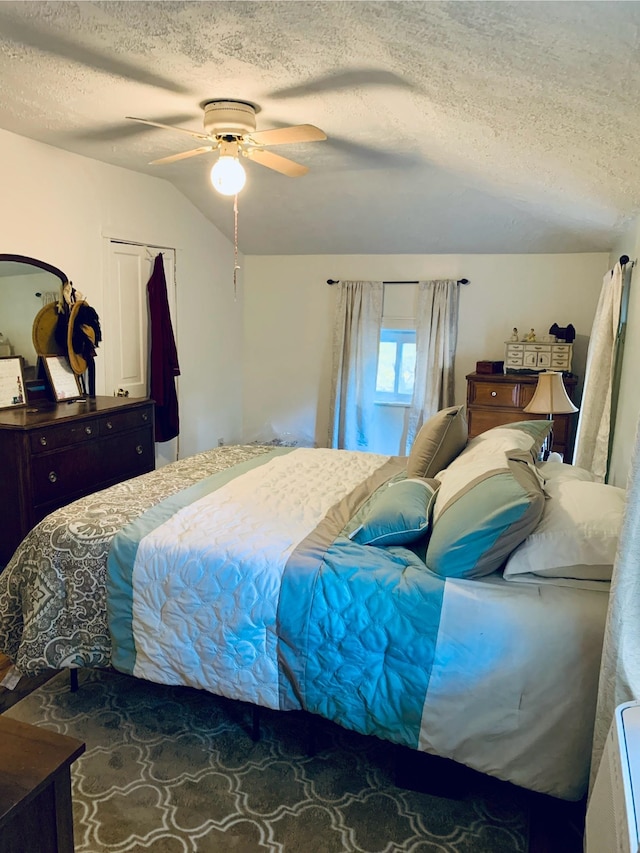 bedroom featuring ceiling fan, a closet, a textured ceiling, and vaulted ceiling