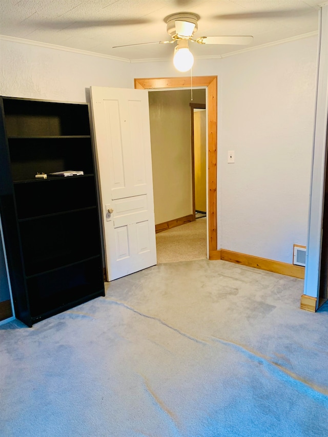 empty room featuring a textured ceiling, ceiling fan, ornamental molding, and carpet floors