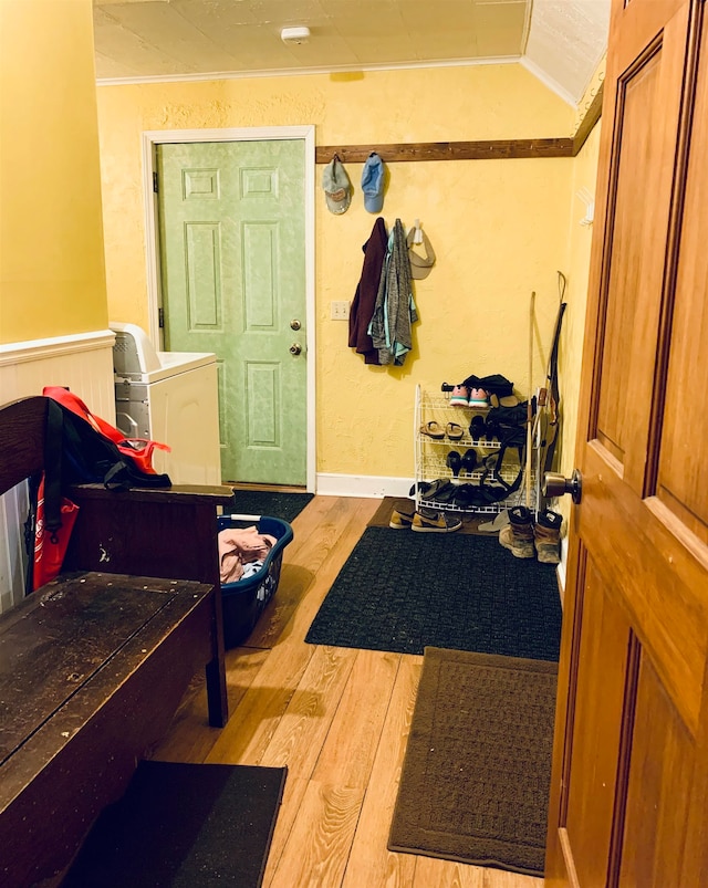 entrance foyer featuring washer / dryer, light hardwood / wood-style floors, ornamental molding, and lofted ceiling