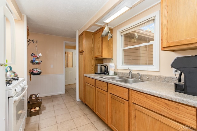 kitchen with light tile patterned flooring, a textured ceiling, white stove, and sink