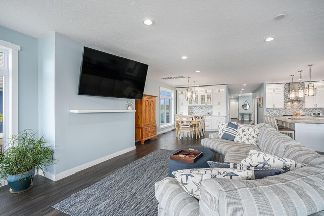 living room featuring dark hardwood / wood-style flooring, a textured ceiling, and an inviting chandelier