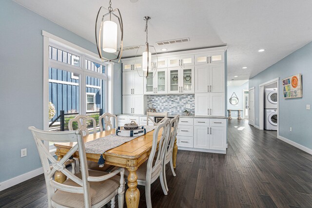 dining room featuring dark hardwood / wood-style flooring and stacked washer / dryer