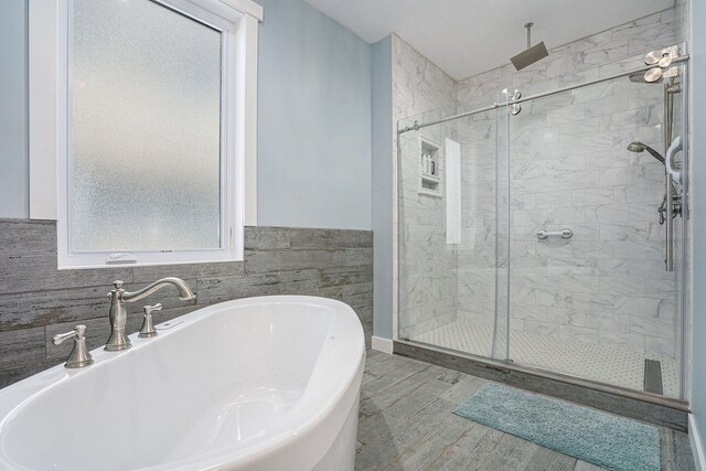 bathroom with shower with separate bathtub, hardwood / wood-style flooring, tile walls, and sink