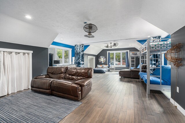 living room featuring a textured ceiling, a wealth of natural light, dark wood-type flooring, and vaulted ceiling