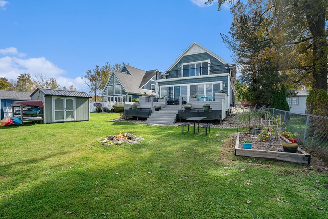 rear view of property featuring a lawn, a wooden deck, and a storage unit