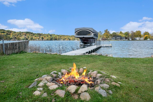 dock area featuring a lawn, a water view, and an outdoor fire pit