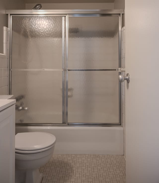 full bathroom featuring tile patterned floors, vanity, toilet, and enclosed tub / shower combo