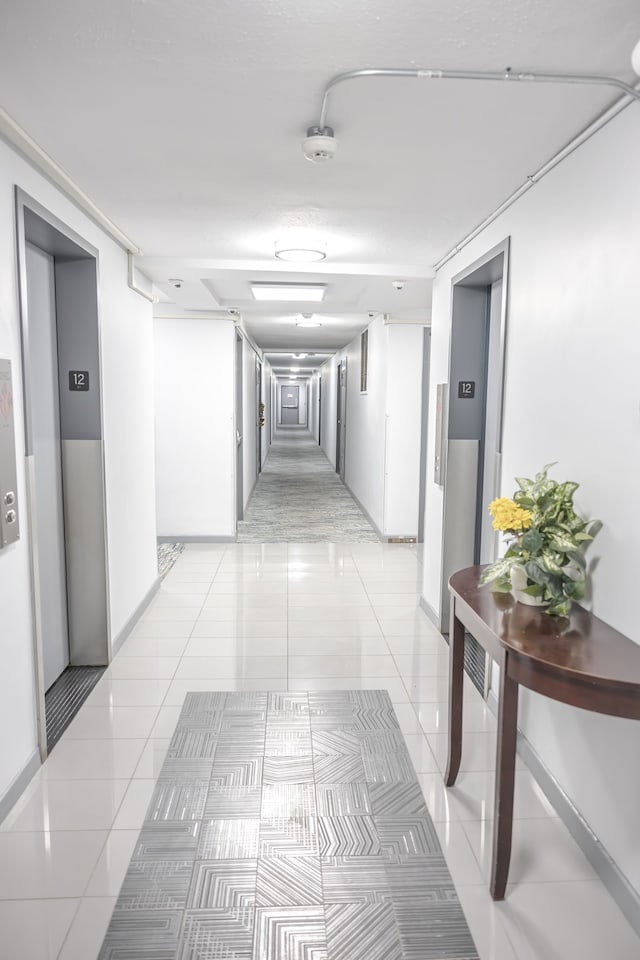 hall featuring elevator and light tile patterned flooring