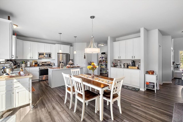 kitchen with pendant lighting, a center island, white cabinets, appliances with stainless steel finishes, and light stone counters