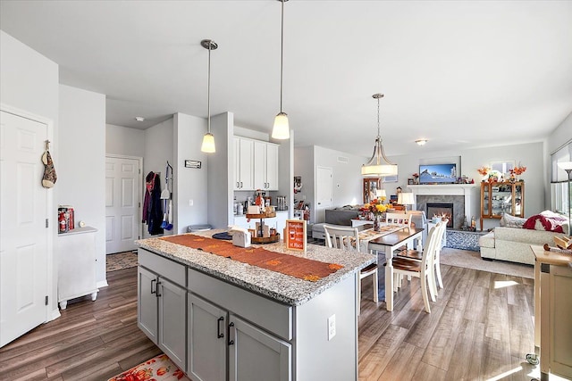 kitchen with dark hardwood / wood-style flooring, a kitchen island, hanging light fixtures, and gray cabinetry