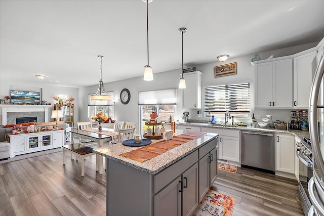 kitchen with a center island, white cabinets, stainless steel appliances, and decorative light fixtures