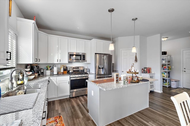 kitchen with appliances with stainless steel finishes, sink, decorative light fixtures, a center island, and white cabinetry