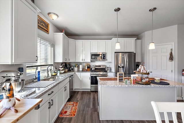 kitchen featuring stainless steel appliances, a kitchen island, decorative light fixtures, dark hardwood / wood-style floors, and white cabinetry