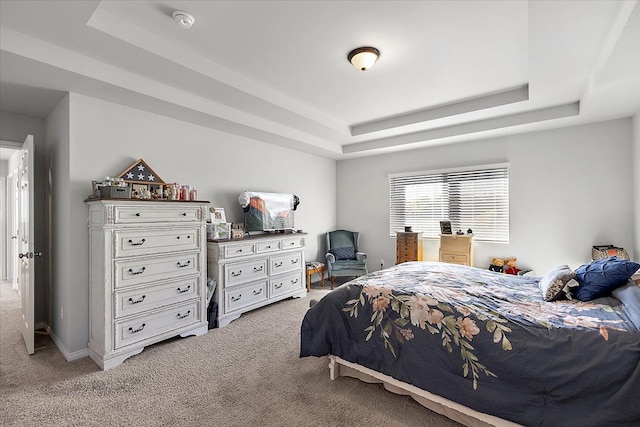 bedroom featuring a tray ceiling and light carpet