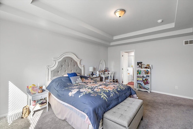 bedroom featuring a raised ceiling, connected bathroom, and carpet