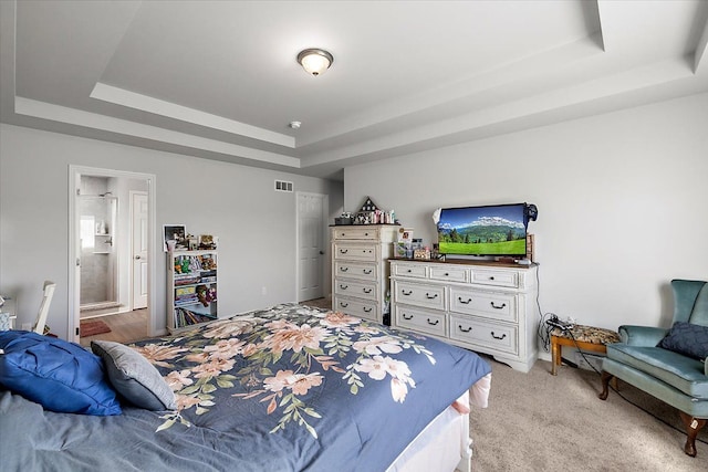 carpeted bedroom with a raised ceiling and ensuite bath