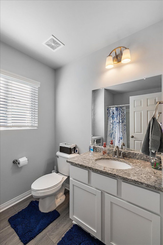 bathroom featuring a shower with shower curtain, wood-type flooring, vanity, and toilet