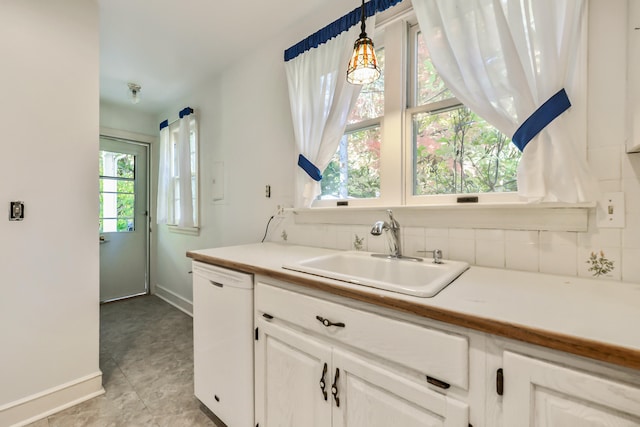 kitchen featuring white dishwasher, a healthy amount of sunlight, sink, and hanging light fixtures