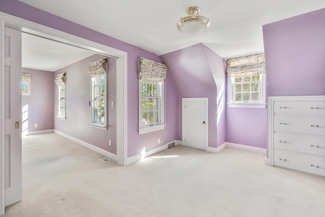 interior space featuring a healthy amount of sunlight, light colored carpet, and vaulted ceiling