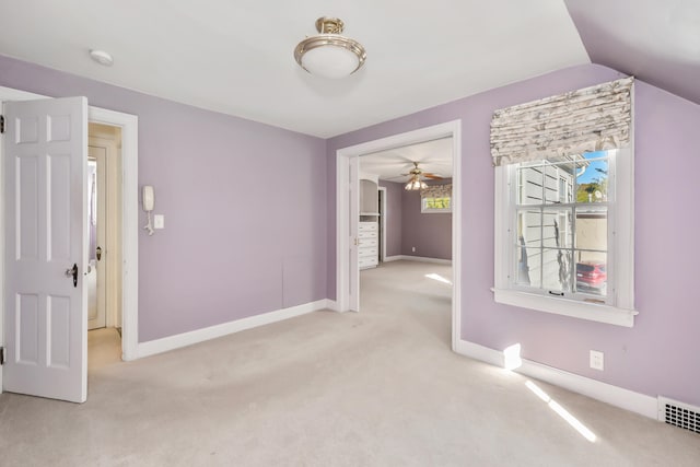 unfurnished room with light colored carpet, vaulted ceiling, and ceiling fan