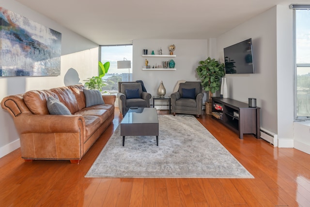 living room featuring baseboard heating, wood-type flooring, and a wall of windows