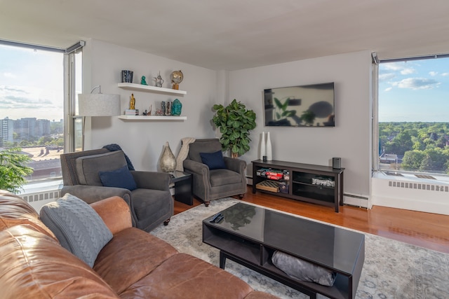 living room featuring light wood-type flooring, a wealth of natural light, and a baseboard heating unit