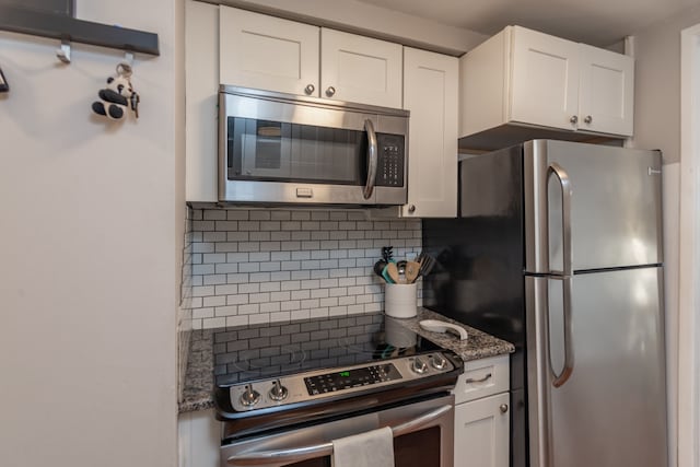 kitchen featuring decorative backsplash, white cabinets, and appliances with stainless steel finishes