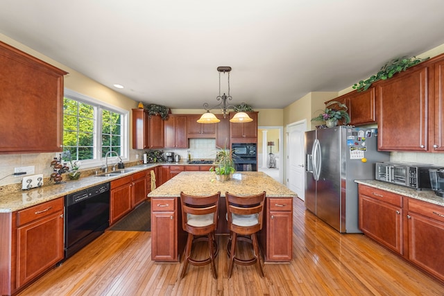 kitchen featuring black appliances, decorative backsplash, light hardwood / wood-style floors, decorative light fixtures, and a kitchen island