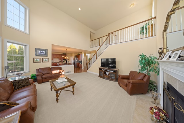 living room with a tile fireplace, light wood-type flooring, high vaulted ceiling, and a notable chandelier