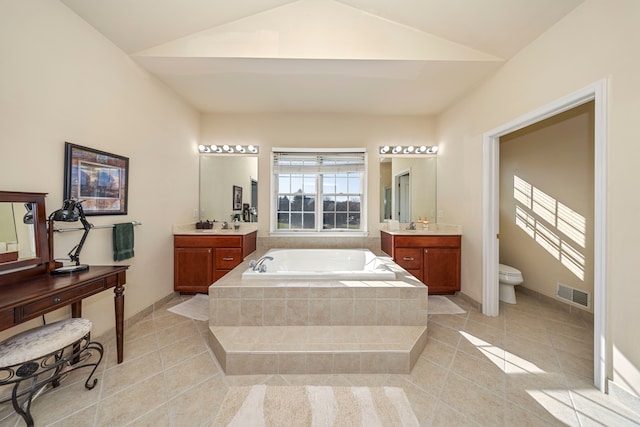 bathroom featuring vanity, tile patterned floors, vaulted ceiling, toilet, and tiled bath