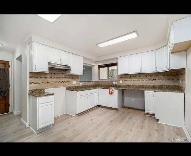 kitchen featuring decorative backsplash, dark stone countertops, white cabinetry, and light hardwood / wood-style flooring