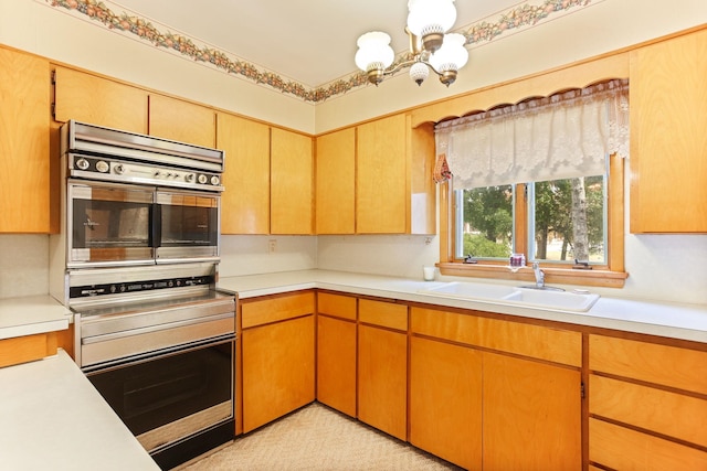 kitchen featuring double oven, light carpet, sink, and a chandelier