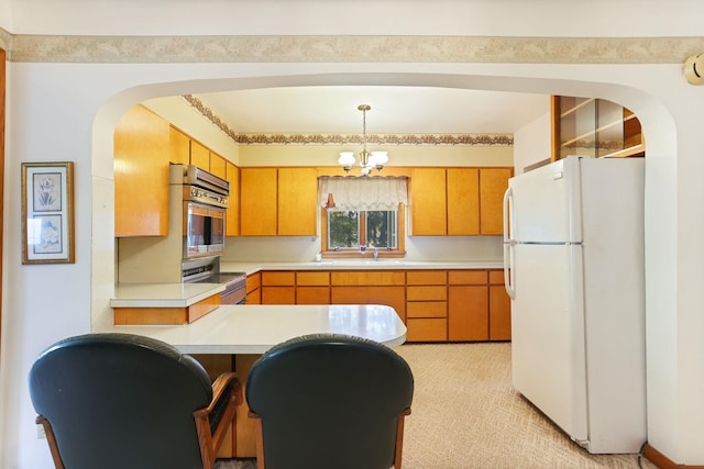 kitchen featuring stainless steel appliances, kitchen peninsula, a chandelier, pendant lighting, and light carpet