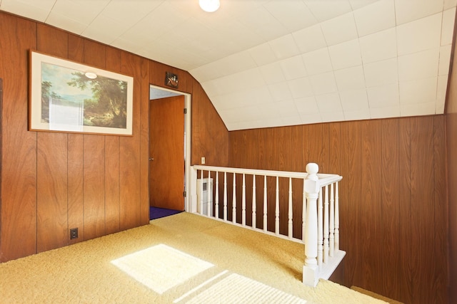 additional living space with carpet floors, vaulted ceiling, and wood walls