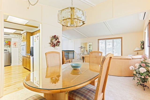 dining room with a chandelier, washer / dryer, light wood-type flooring, and a wall unit AC