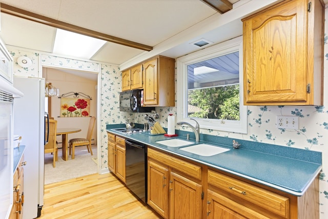 kitchen featuring black appliances, light wood-type flooring, and sink