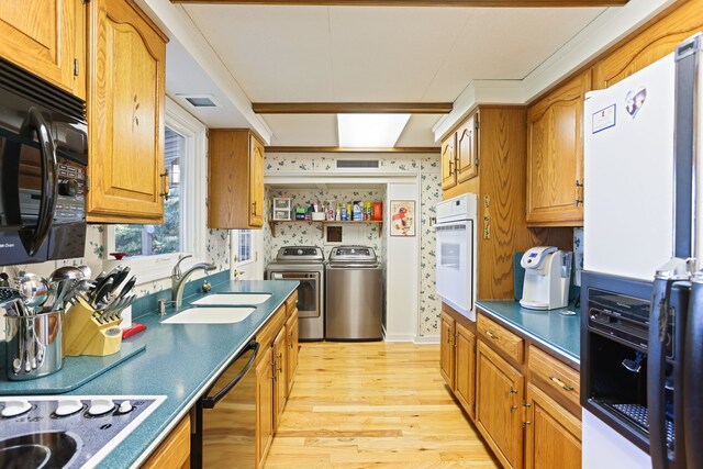 kitchen with black appliances, washer and dryer, light hardwood / wood-style floors, and sink